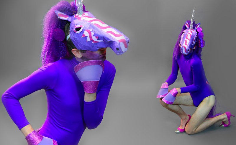Two figures in purple unicorn masks, bodysuits, and hooves pose against a gray background.