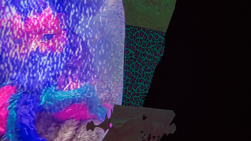 Abstract artwork featuring a textured blue and pink section alongside a green leopard print panel, with a dark, jagged silhouette against a black background.