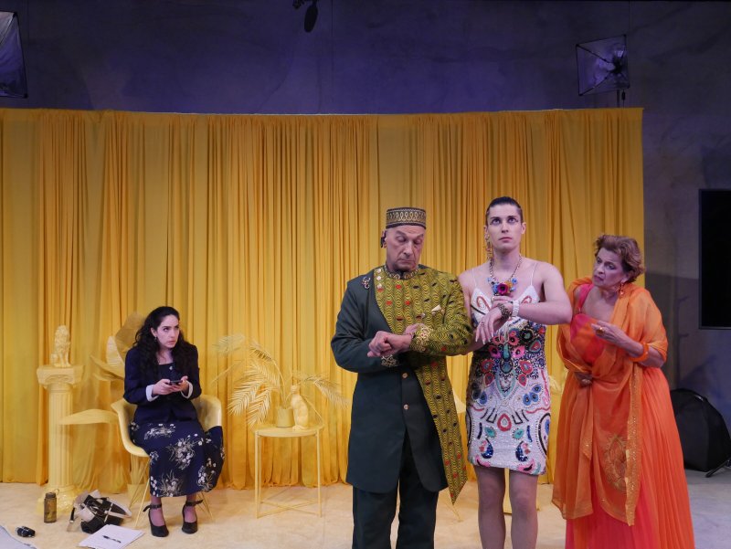 Four actors on stage: two women seated and standing on the left, two women and a man standing on the right.