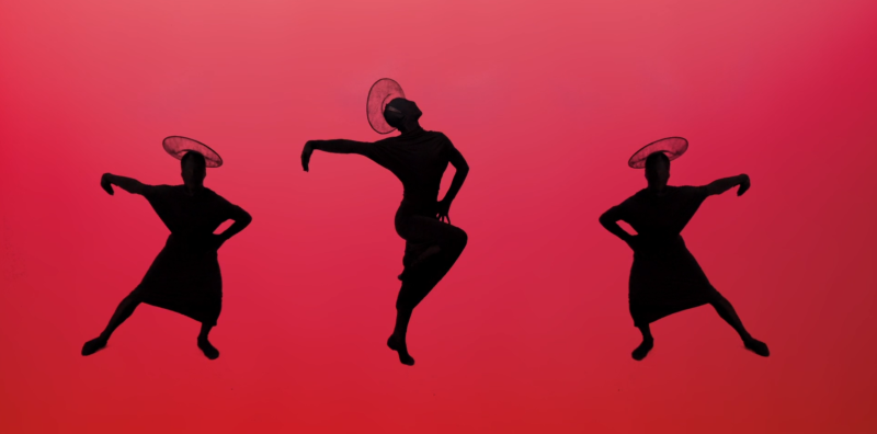 Three black silhouettes of figures in hats dancing against a vibrant red background.