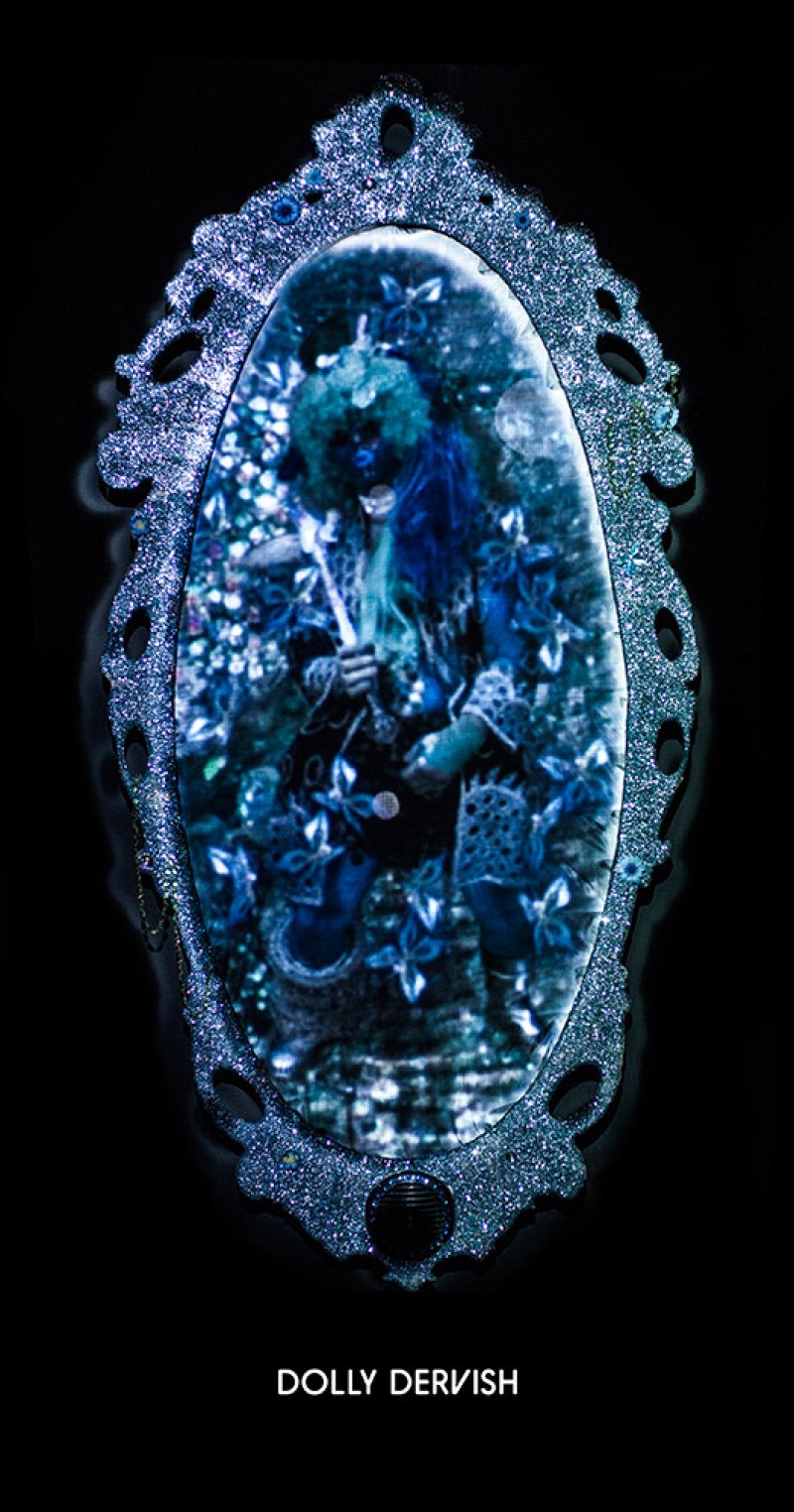 Ornate, glittery silver mirror frame with an oval screen displaying a blue-toned figure in a forest, holding a staff.