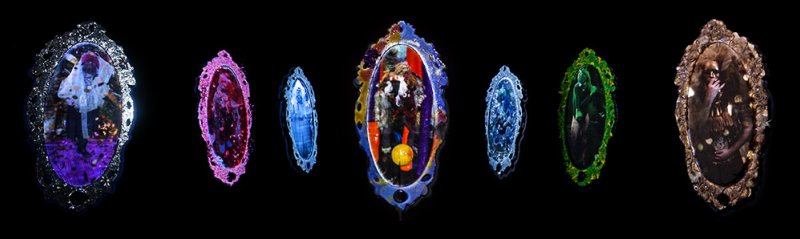 Seven ornate, colorful mirrors on a black background, each reflecting a unique, abstract, and distorted scene.